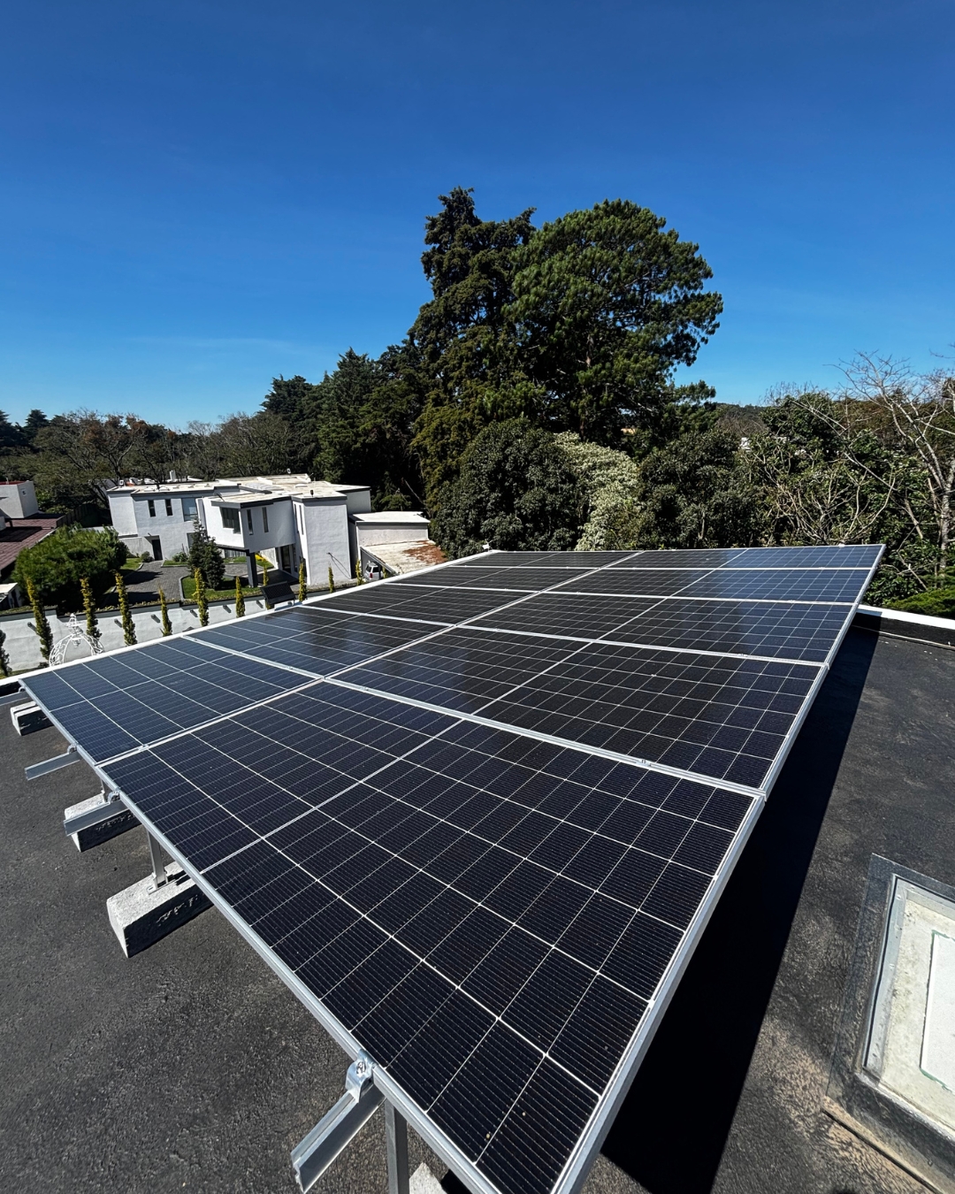 Sistema solar residencial sobre techo plano con vista al bosque